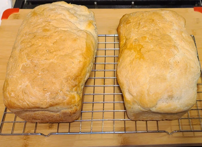 two loaves of peasant bread on a cooling rack